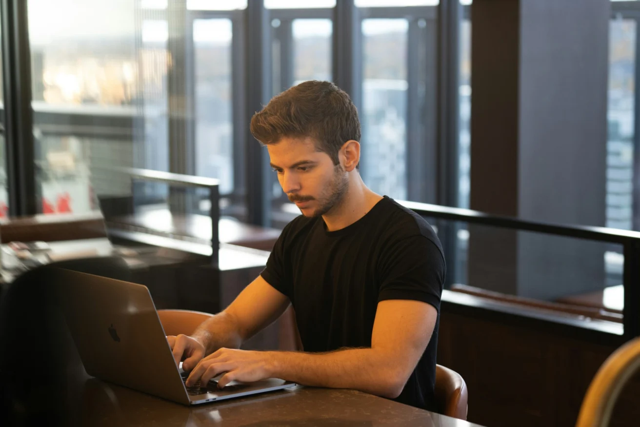 Man working on a laptop in a modern office, representing vigilance and awareness against AI-powered cyber threats
