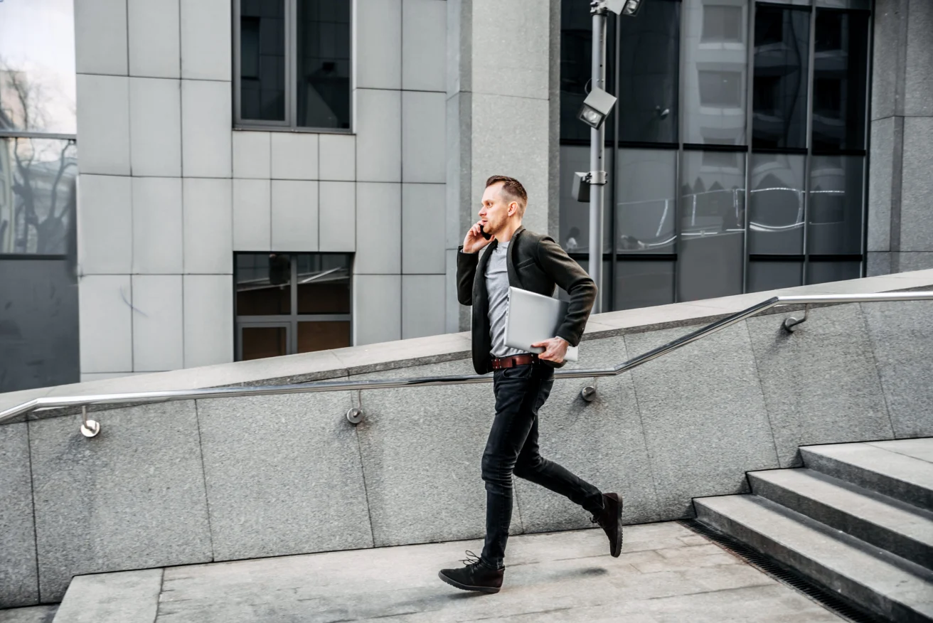 man with a laptop runs up the stairs to the office