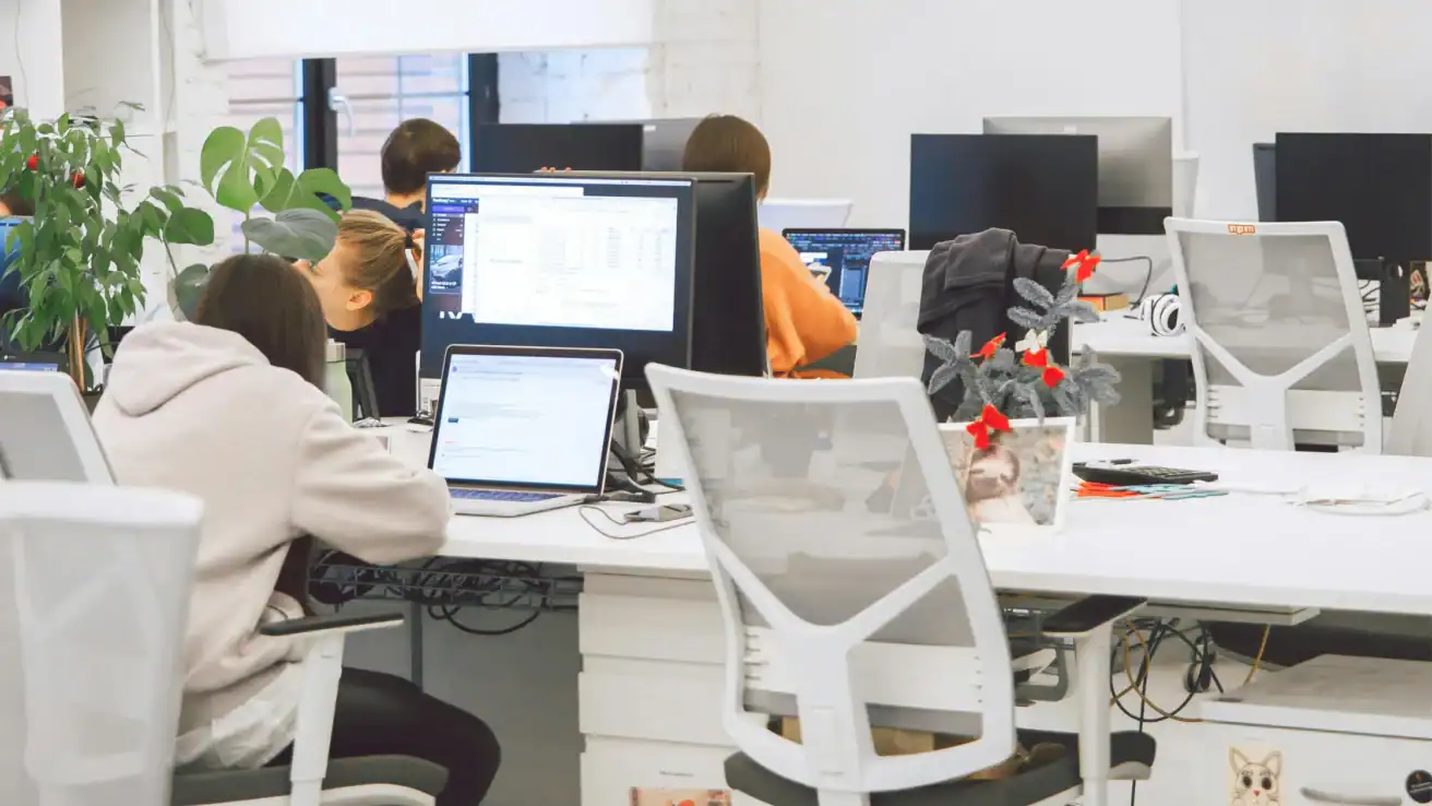 Employees working at computers in a modern open-plan office workspace