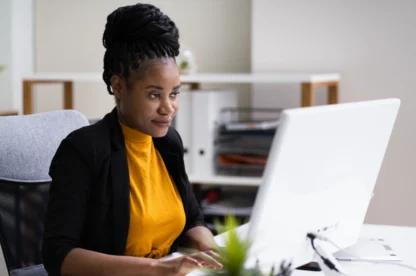 Professional woman working at a desktop computer in a modern office, focused on reviewing content on her screen